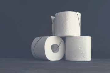White toilet paper rolls on wooden table. Black background. Selective fcus. Copy space.