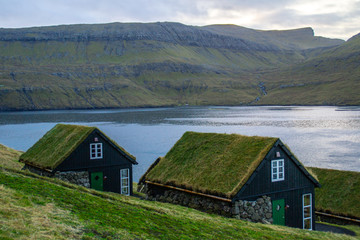 Fototapeta na wymiar Traditional nordic Scandinavian village houses with green grass roof. Iconic scenic view of Faroe Island, Denmark, Europe. Beautiful tourist spot located at Vágar Island. Moody weather scene. 