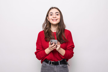 Fototapeta na wymiar Smiling young woman in gray sweater, scarf using mobile phone typing sms message isolated on grey background.