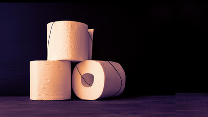 White toilet paper rolls on wooden table. Black background. Selective fcus. Copy space.