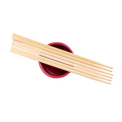 Japanese sushi sticks or chopsticks over red sauce bowl isolated on white background. Top view