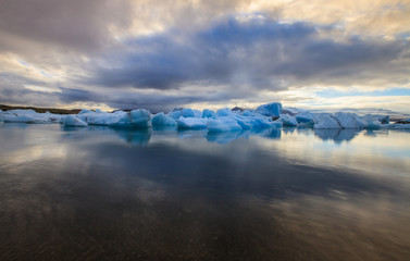 Dramatic a sunset with mirror water with blue iceberg pieces in Jokulsarlon lagoon, Iceland.