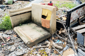 Used sofas with garbage in the landfill