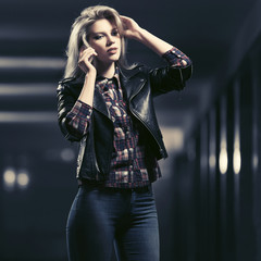 Young fashion blond woman in leather jacket calling on cell phone