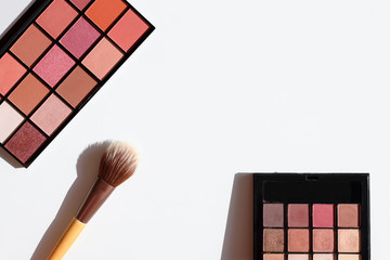 Top view of make up cosmetics and accessories. Eye shadow palettes in pink, red and brown colors...