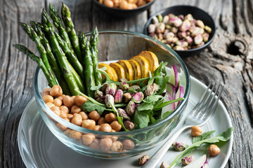 Vegetarian salad, Buddha bowl with asparagus, arugula, zucchini, kohlrabi, pistachio and chickpeas. Selective focus, rustic style