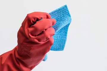Woman’s hand in red rubber glove with blue cleaning napkin isolated on white background.