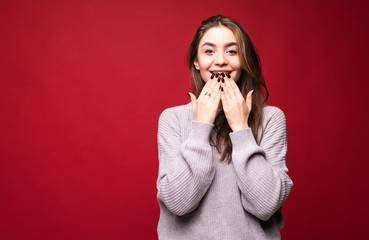 Photo of screaming excited young woman standing isolated over red background.