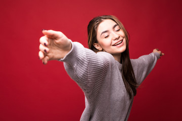 Dancing happy cheerful woman in red in joyful dance. Energetic portrait of joyous beautiful young woman on red background.