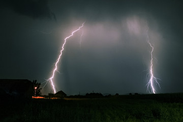 Bright branched lightning bolts hit the earth in the foothills of the Carpathian Mountains in...