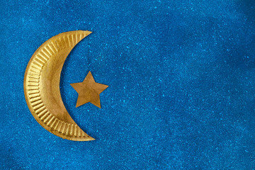 Diy Ramadan kareem crescent moon with a star from a disposable cardboard plate and gold paint.
