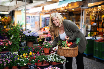 Frau freudig lachend kauft Blumen auf dem Markt 
