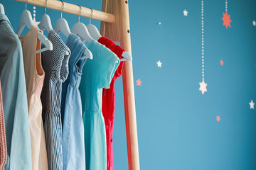 Rack with children's clothes on color background
