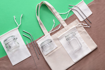 Fabric bags, glass jars and metal straws on color background. Zero waste concept