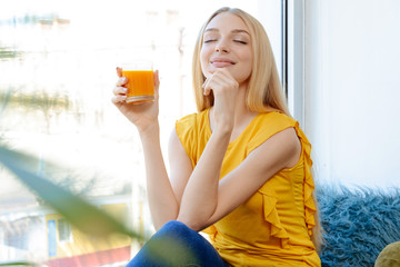Beautiful young woman drinking fresh juice at home