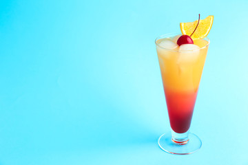 Glass of Tequila Sunrise cocktail on color background
