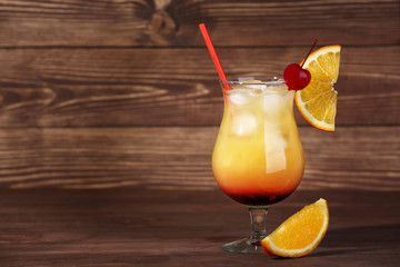 Glass of tasty Tequila Sunrise cocktail on wooden background