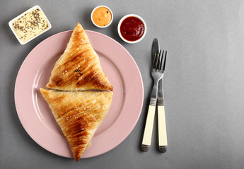 Plate with delicious samosas and sauces on grey background