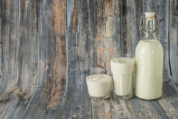 Milk kefir and sour cream are in a row on a wooden background. Fresh dairy products for breakfast
