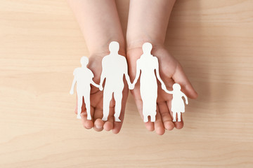 Child's hands with figure of family on light background. Concept of adoption
