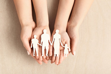 Hands of woman and child with figure of family on light background. Adoption concept