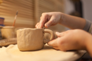 Female potter works with ceramic at his workshop. Young woman work inside 