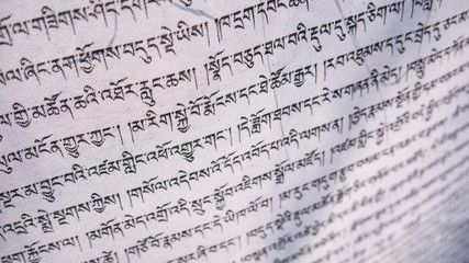 Tibetan letters on white textile. Religious writing. Prayer flags. Mantra. Buddhism. Calligraphy