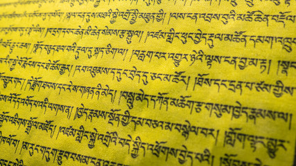 Tibetan letters on yellow textile. Religious writing. Prayer flags. Mantra. Buddhism. Calligraphy