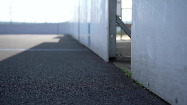  View to inline skates riding on empty playground. Outdoor inline skating on smooth concrete ground. Before the big tournament. Empty ice hockey playground - view from behind the gate. 