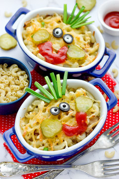 Naklejki Fun food idea for kids - american mac and cheese macaroni pasta baked with cheesy sauce decorated with vegetables like a smiling funny face