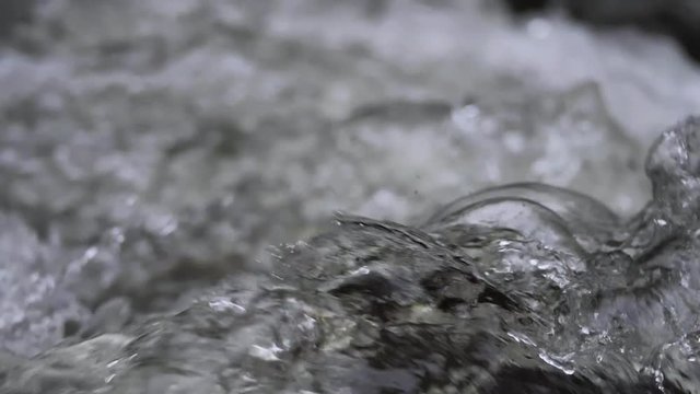 Rushing river water splashing creating waves extreme close up in slow motion