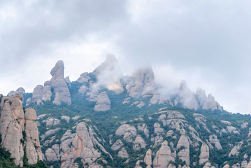 Hazy unusual mountains with green trees and cloudy sky near Montserrat Monastery,Spain