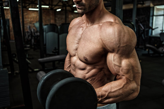 Brutal strong athletic men bodybuilder trains in the gym