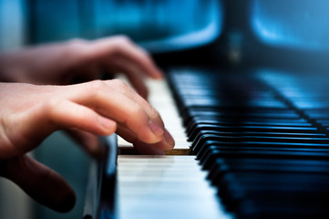 Fototapeta premium Playing the piano, hands pressing the keys with shallow depth of field