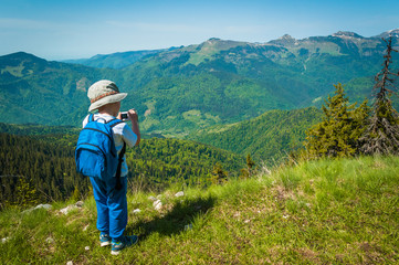 Child taking photo of beautiful mountain landscape setting