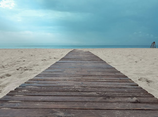 Fototapeta premium Wooden walkway leading from the beach to the sea with an intense blue sky.