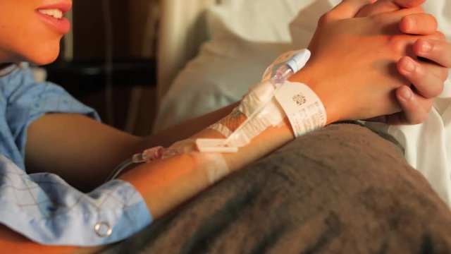 Woman Nervously Squeezes Hands In Hostial With Iv In Arm. Woman squeezes her hands together while in labor in the hospital.