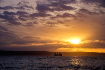 Naklejka na ściany i meble Sunset over Puget Sound as a ferry crosses through the light