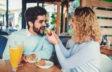 Beautiful young couple sitting in a cafe, having breakfast. Love, dating, food, lifestyle concept