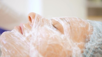 The concept of a beautician. The hands of a cosmetologist put a film on the face of a woman. anesthesia before the procedure of mesotherapy, biorevitalization or contour plastics