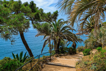 Stone staircase on hiking trail along the cliffs for tourists in the beautiful summer garden on the Mediterranean sea coast. Blanes, Catalonia, Spain.