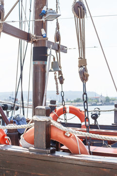 View on part of old wooden sailboat with bright sky background. Orange lifelines. Old deadeye with cables on the shrouds of a sailing ship in Varna, Bulgaria.