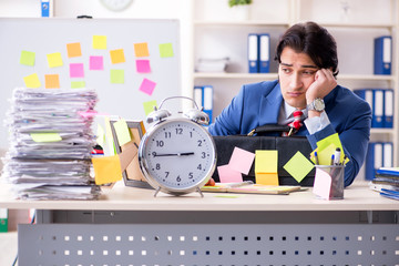 Young male handsome employee in conflicting priorities concept 