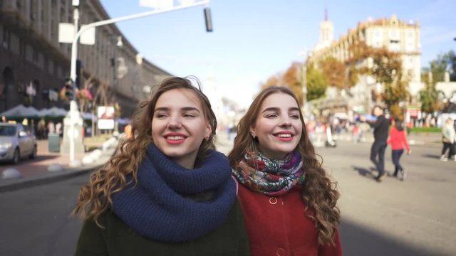   4k. Young women sister twins walk in city street with smile. Steady portrait shot