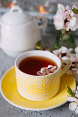 Tea served in a yellow teacup and saucer decorated with spring flowers