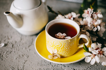 Tea served in a yellow teacup and saucer decorated with spring flowers