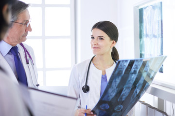 Smiling doctors discussing patient's diagnosis looking at x-rays in a hospital