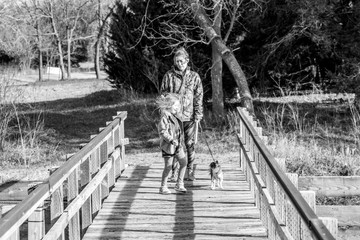 black and white photo mother and daughter walking along bridge 