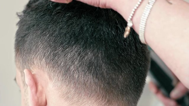 Female Barber is Working and Cutting Hair by Clipper on Back of Head of Young Caucasian Brown-haired Man in Hairdressing or Barbershop Salon. Close Up Slow Motion 4K shot Backside view