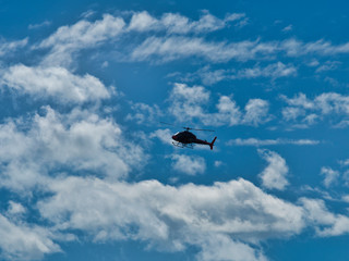 Flying helicopter airplane in blue sky with clouds